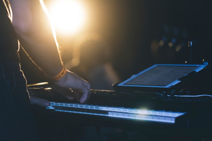 Musician playing a keyboard with a tablet