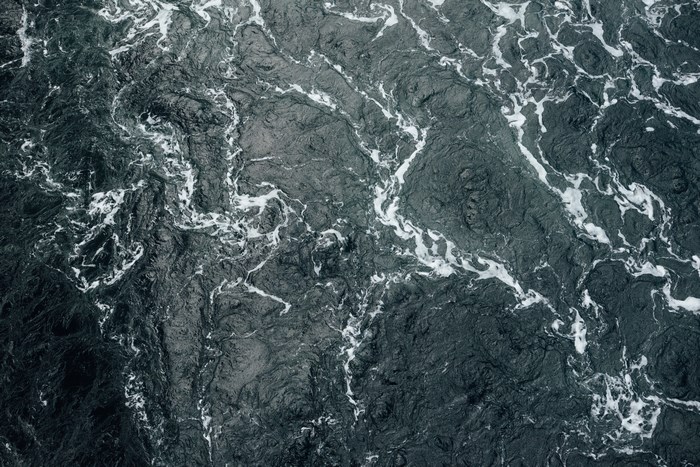 Dark rough water with white foam from a bird's eye view