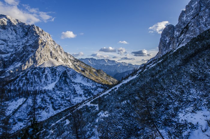 Snowy mountain range under a blue sky with clouds