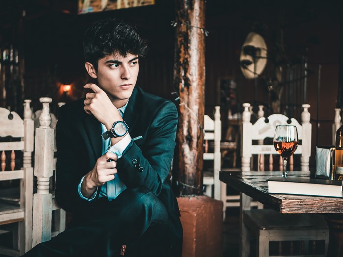Man in suit adjusting cufflink in restaurant
