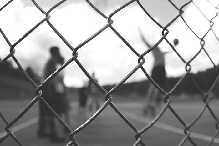 People playing basketball behind a chain-link fence