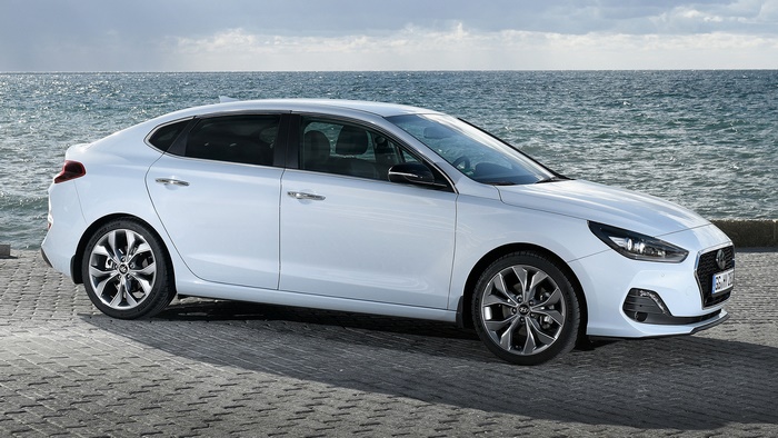White Hyundai i30 Fastback parked by the sea