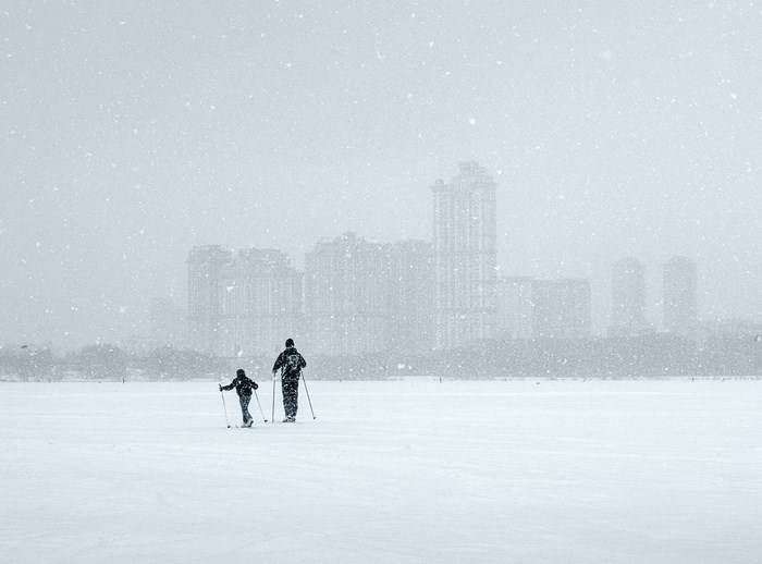 Two people cross-country skiing in a snowy city