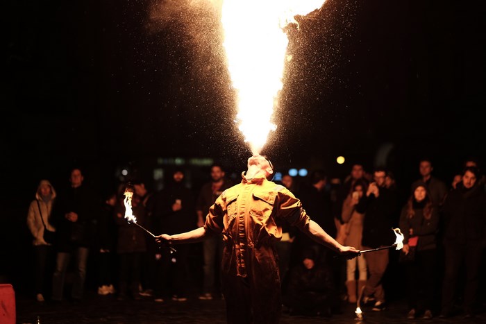 Man breathes fire in front of a crowd at night