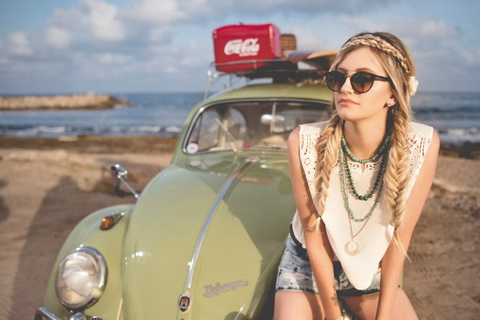 Woman with braids and sunglasses by a vintage VW Beetle