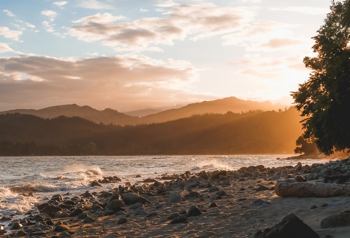 Golden hour sunset over mountains and rocky coastline