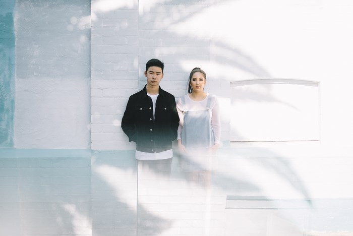 Asian couple posing against a white brick wall