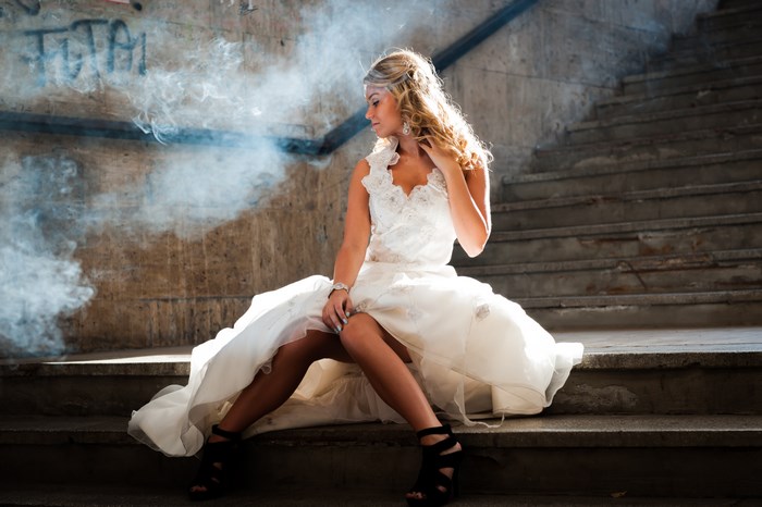 Bride in White Dress Sitting on Stairs with Smoke