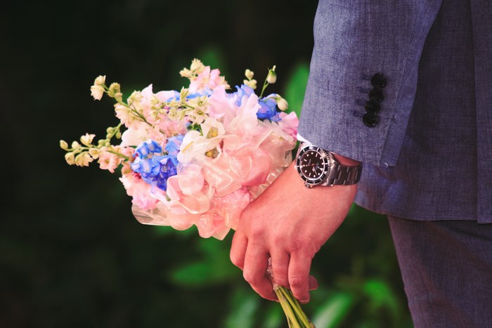 Man in suit holding a bouquet with a watch