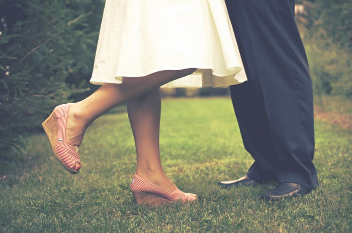 Couple in wedding attire standing on grass