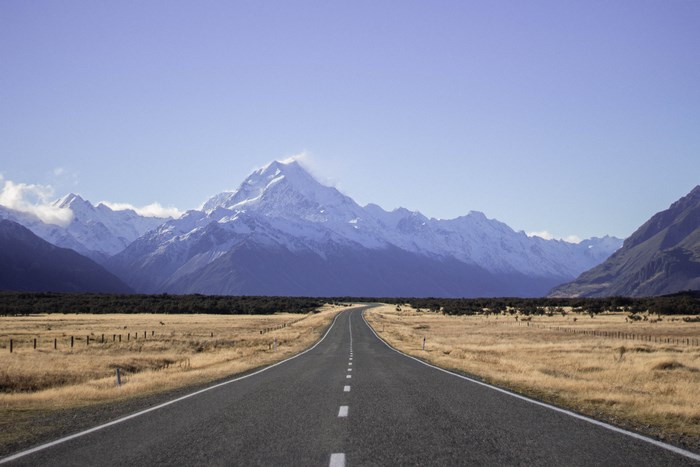 Straight Road Leading to Snow-Capped Mountains in New Zealand