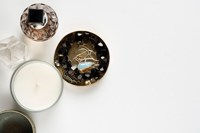 Perfume bottle, candle, and jewelry in a bowl