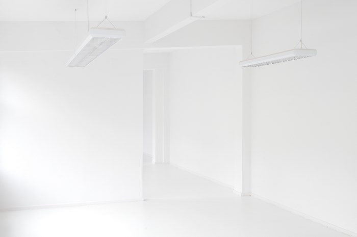 White room with hanging fluorescent lights and corridor
