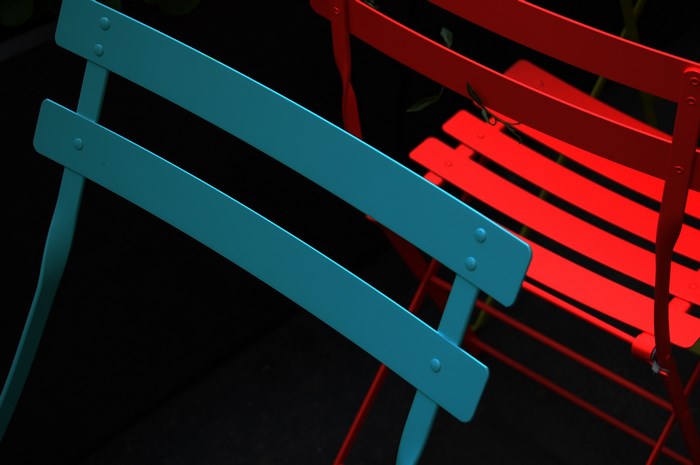 Two chairs, one blue and one red, against a black background