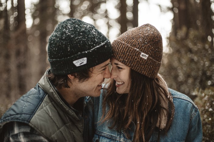 Couple wearing beanies in a snowy forest