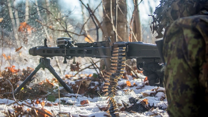 Soldier firing a machine gun in a snowy forest