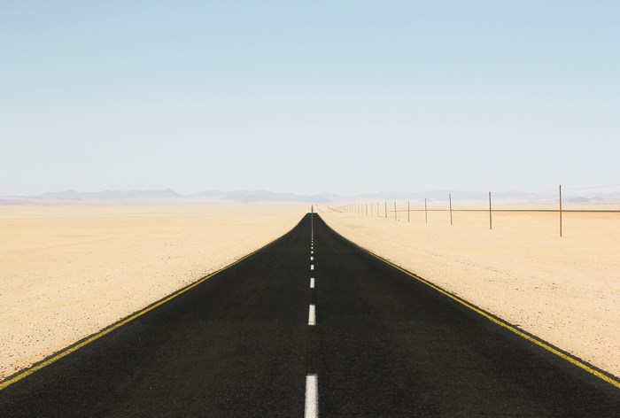 Desert road with telephone poles and mountains