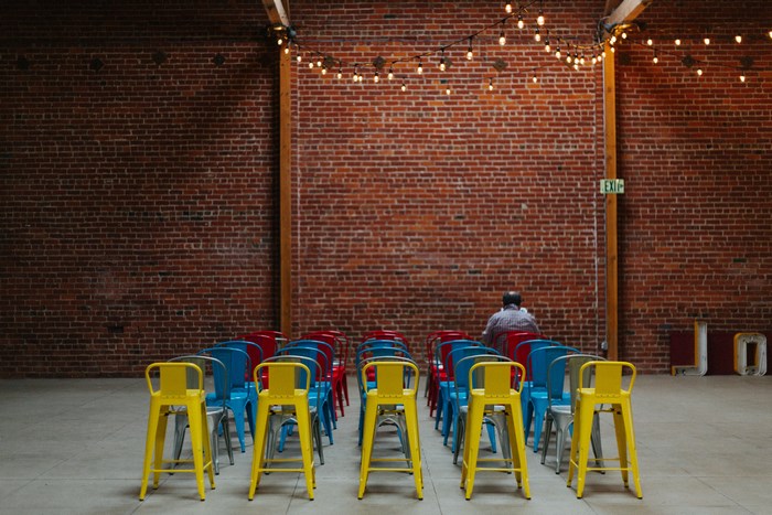 Chairs lined up in front of a brick wall with a person sitting