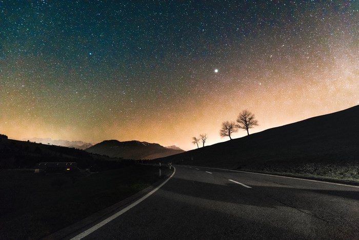 Starry Night Sky Over Quiet Highway with Silhouetted Trees
