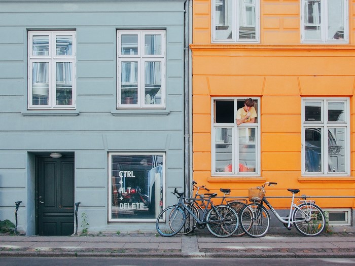 Person looking out window of orange building with bicycles