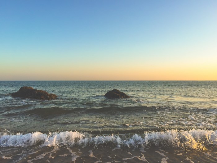 Ocean waves crash on a rocky shore at sunset