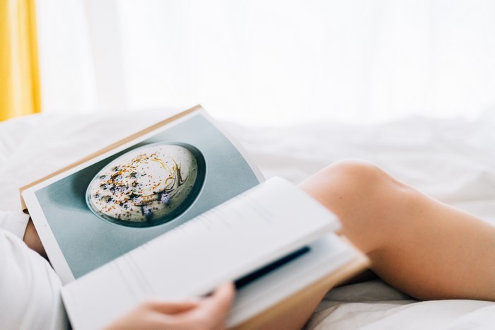 Person reading a recipe book in bed