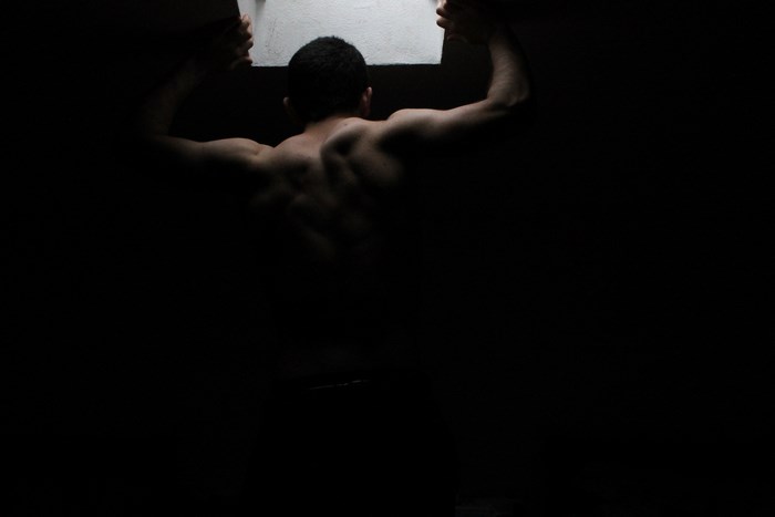 Man with muscular back holding a light source