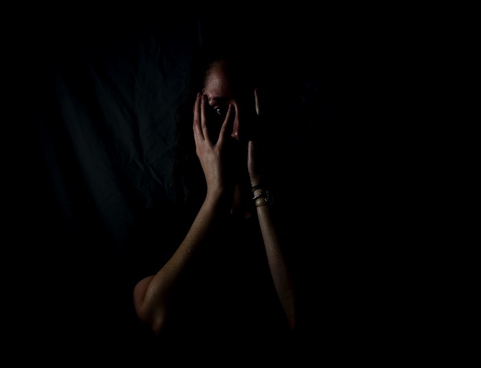 Woman covering her face in darkness