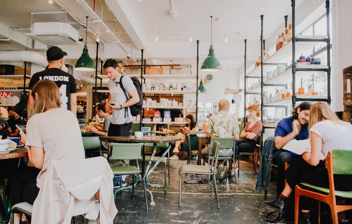 People sitting at tables in a London cafe with shelves