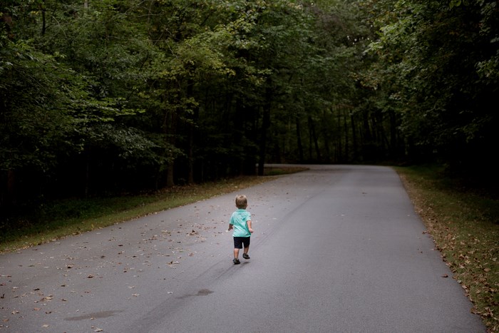 Boy running on a road in a forest
