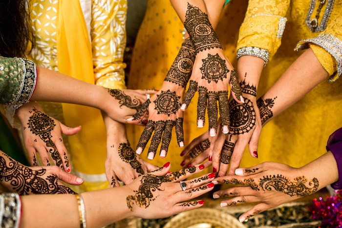 Hands decorated with intricate henna designs at a celebration