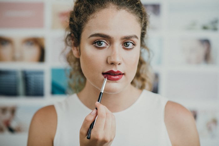 Woman applying red lipstick with a brush
