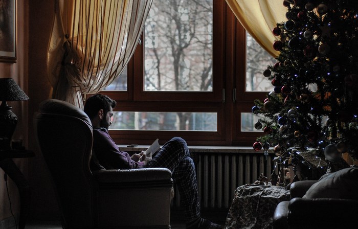 Man reading a book by a Christmas tree