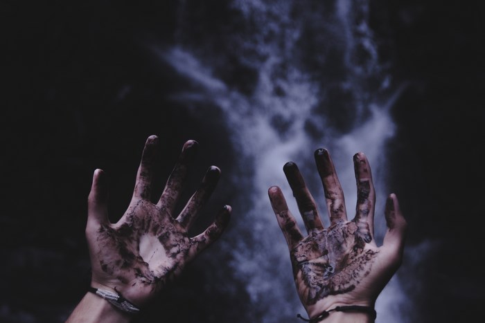 Dirty hands reaching up against a dark background