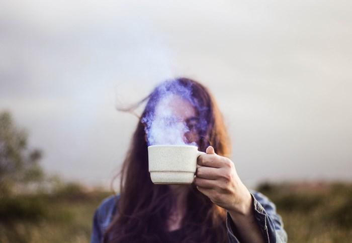 Woman holding a steaming mug outdoors