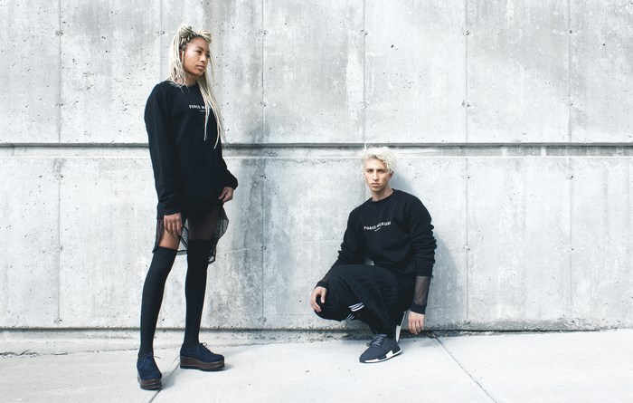 Man and woman in black sweaters against concrete wall