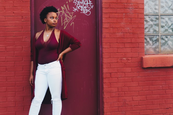 African American woman in burgundy cardigan and white jeans