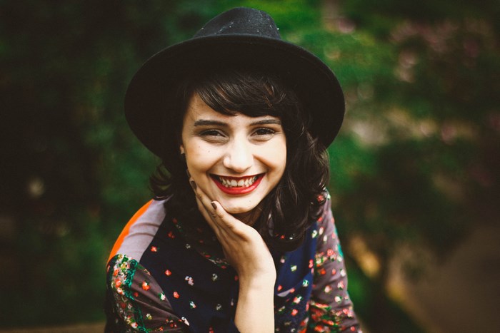 Woman in a hat smiling outdoors
