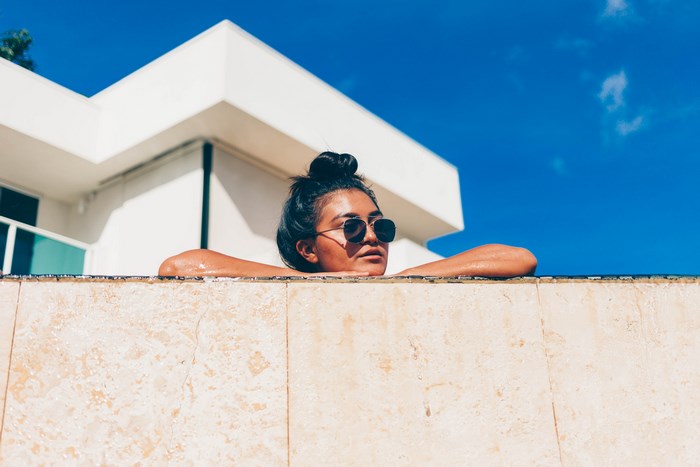 Woman in sunglasses relaxing by a pool