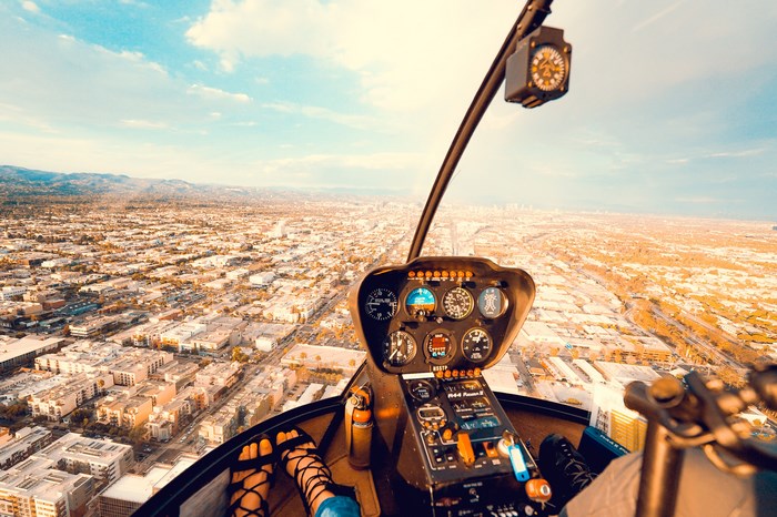 Helicopter cockpit view over a sprawling cityscape