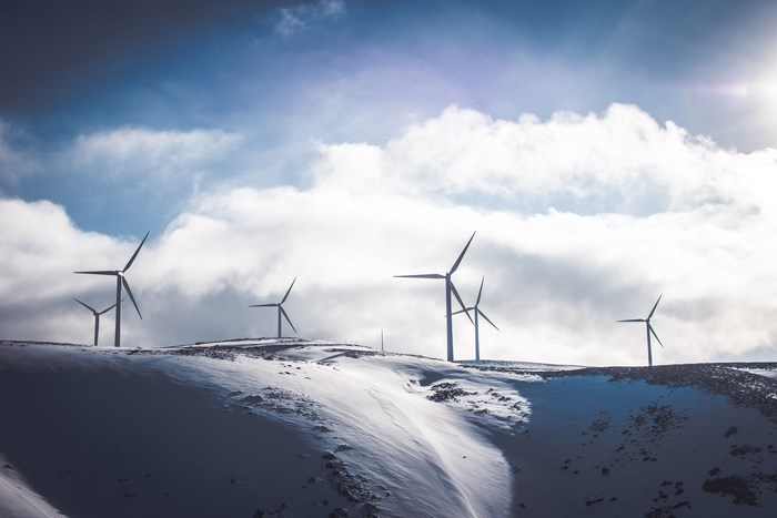 Wind turbines on a snowy hill under a cloudy sky