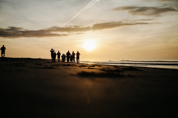 People running on a beach at sunrise