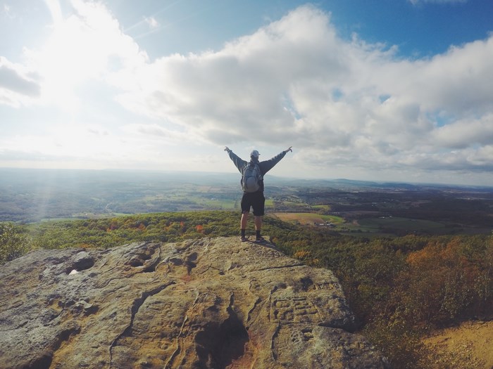 Hiker with arms raised on a rocky mountain overlook