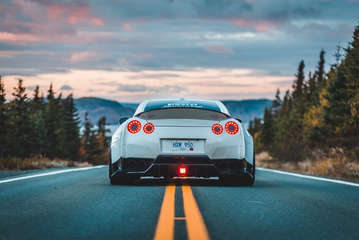 White Nissan GT-R on a road with trees and mountains