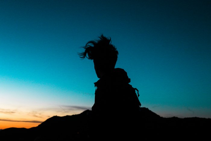 Silhouette of a person with windblown hair at sunset