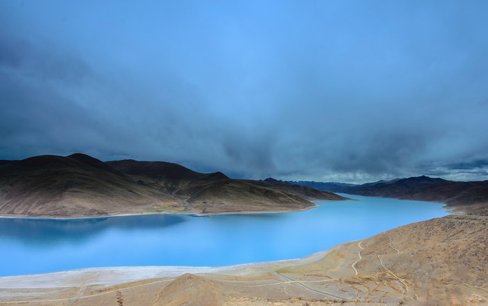 Blue lake and mountains under stormy sky in China