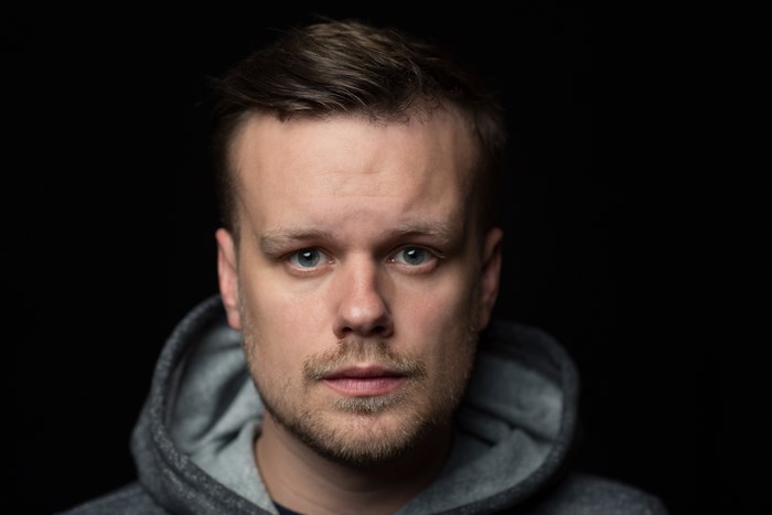 Man with beard wearing a grey hoodie in studio