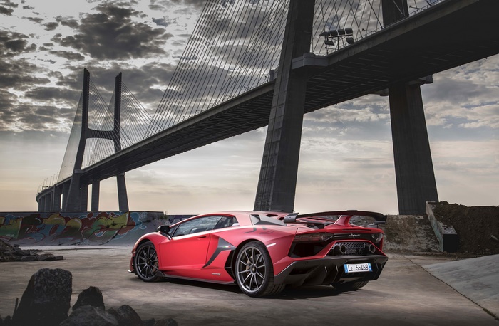 Red Lamborghini Aventador SVJ under a bridge