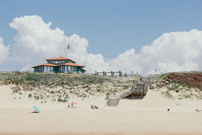 Building on sand dunes with beachgoers and stairs