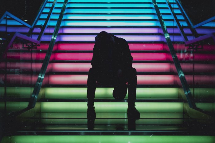 Person sitting on colorful illuminated stairs